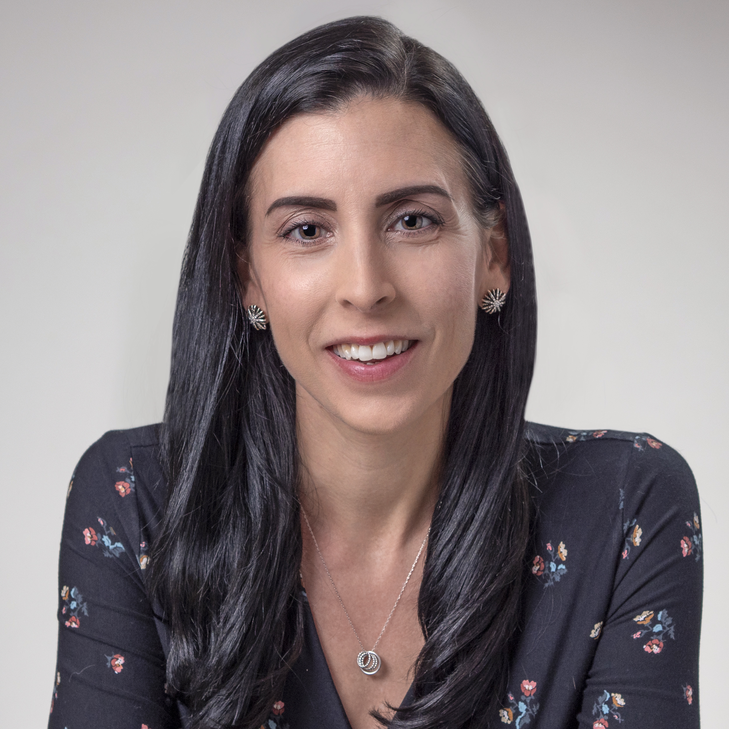 Holly Fernandez-Lynch. A woman with long black hair smiles at the camera. She is wearing a black blouse.