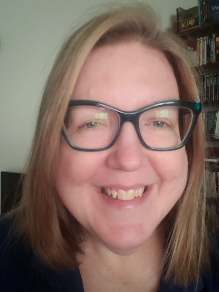 Gwyneth M. Eliasson. A blond, pale-skinned woman wears glasses in an extreme close up.